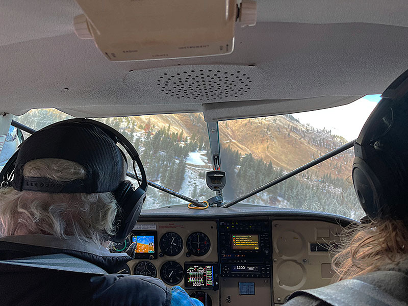 11-Mike-at-the-controls-landing-McClain-Ranch-short-strip-is-visible-in-the-center-of-the-wind-screen.-RH-Holm-Jr.-Photo